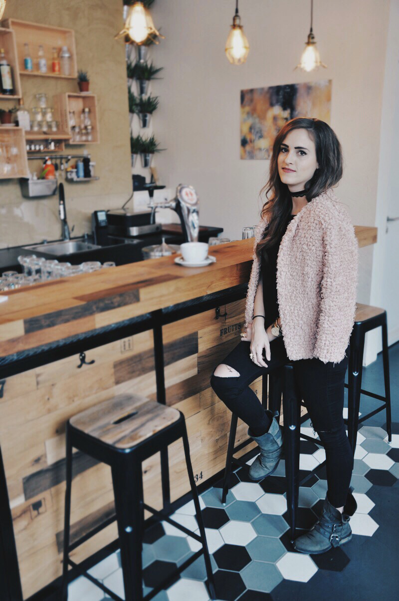 Flausch-Jacke Chloé von TooChé mit einer schwarzen engen Hose von Topshop. Dazu ein Basic Shirt von H&M und Boots von Steve Madden. Die schwarze Umhängetasche ist von River Island. Make-up und Lippenstift sind von MAC Cosmetics.