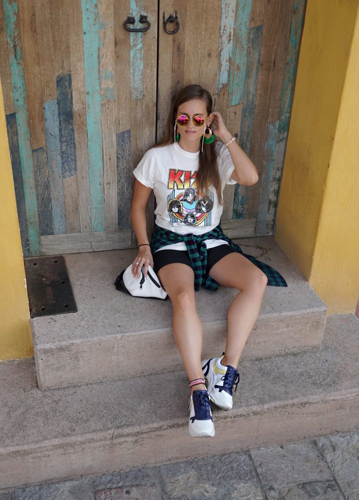 Andrea Steiner vom Mode Blog Strawberries 'n' Champagne aus der Schweiz trägt schwarze kurze Leggings mit einem Band Shirt von Kiss, plateau Sneakers und eine kartiertes Hemd.