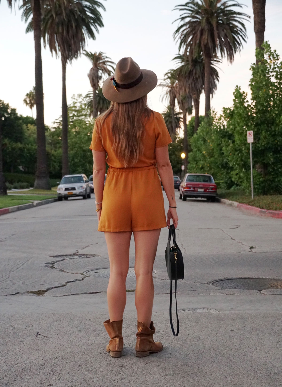 Andrea Steiner vom Mode Blog Strawberries 'n' Champagne aus der Schweiz trägt einen Jumpsuit, Boots, Tasche und einen selbst kreierten Hut.