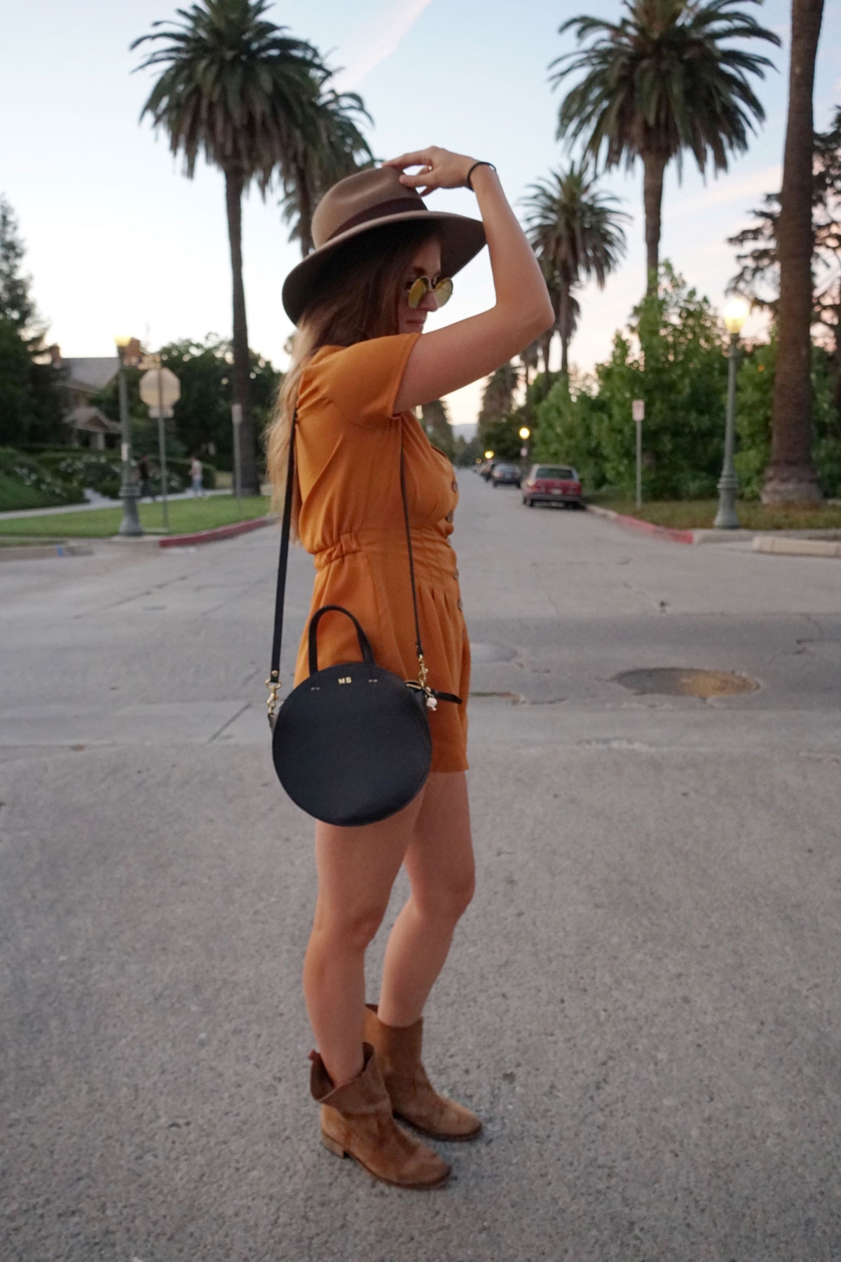 Andrea Steiner vom Mode Blog Strawberries 'n' Champagne aus der Schweiz trägt einen Jumpsuit, Boots, Tasche und einen selbst kreierten Hut.