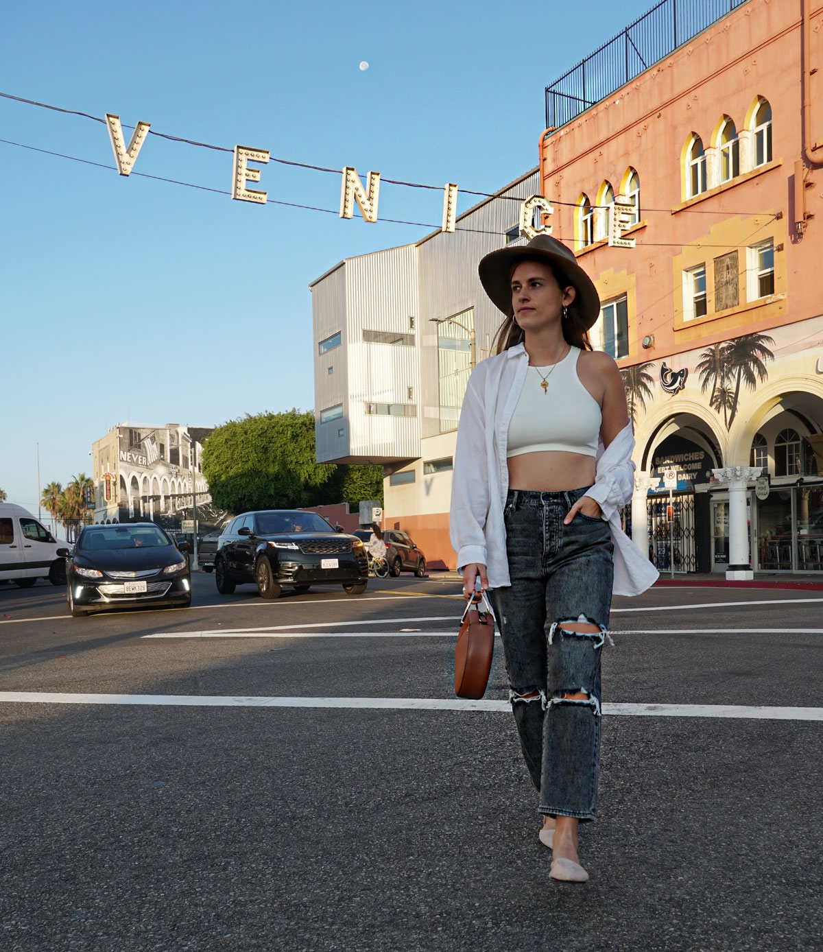 Andrea Steiner, fashion blogger from Strawberries 'n' Champagne based in Switzerland wears black mom jeans with a white cropped top and a oversize blouse.