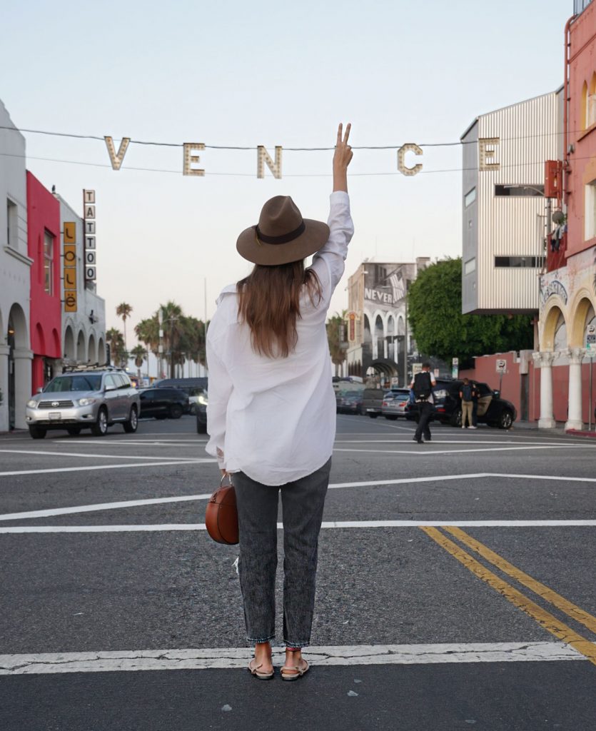 Andrea Steiner, fashion blogger from Strawberries 'n' Champagne based in Switzerland wears black mom jeans with a white cropped top and a oversize blouse.